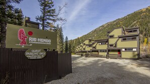 Hinweisschild für Gäste parkplätze der Rio Hondo Eigentumswohnungen, mit Holzzaun und einem Schotterweg, der zu einem Gebäudekomplex führt.