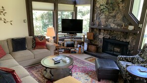 Ein gemütliches Wohnzimmer mit Sofa, Hocker, Couchtisch und Kamin.