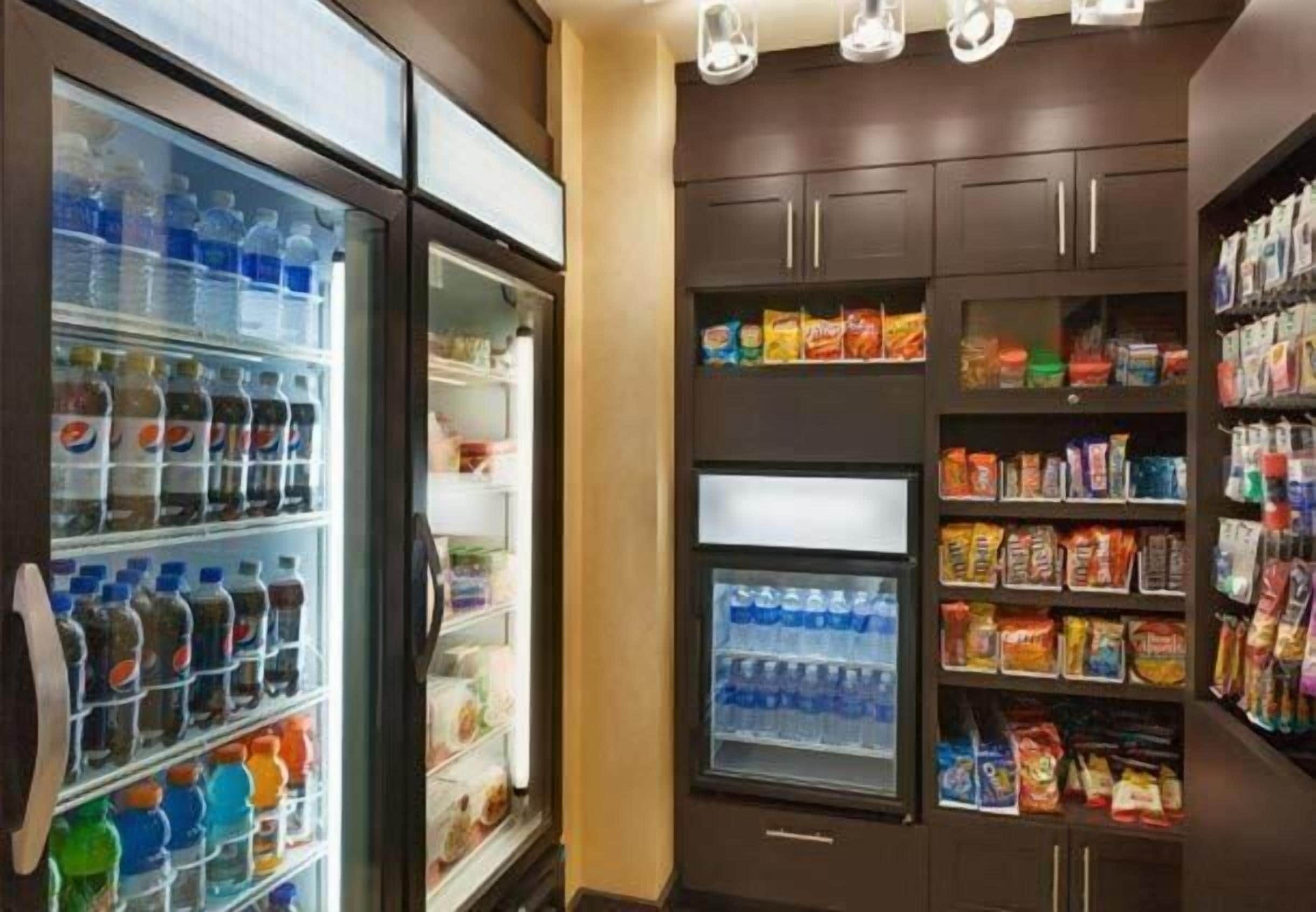 Una despensa de hotel con estantes llenos de agua embotellada, bocadillos y otros alimentos.