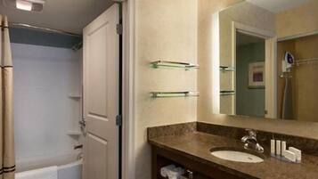 A bathroom with a bathtub, a sink, and a mirror. There are towel racks above the sink and a shower curtain visible in the background.