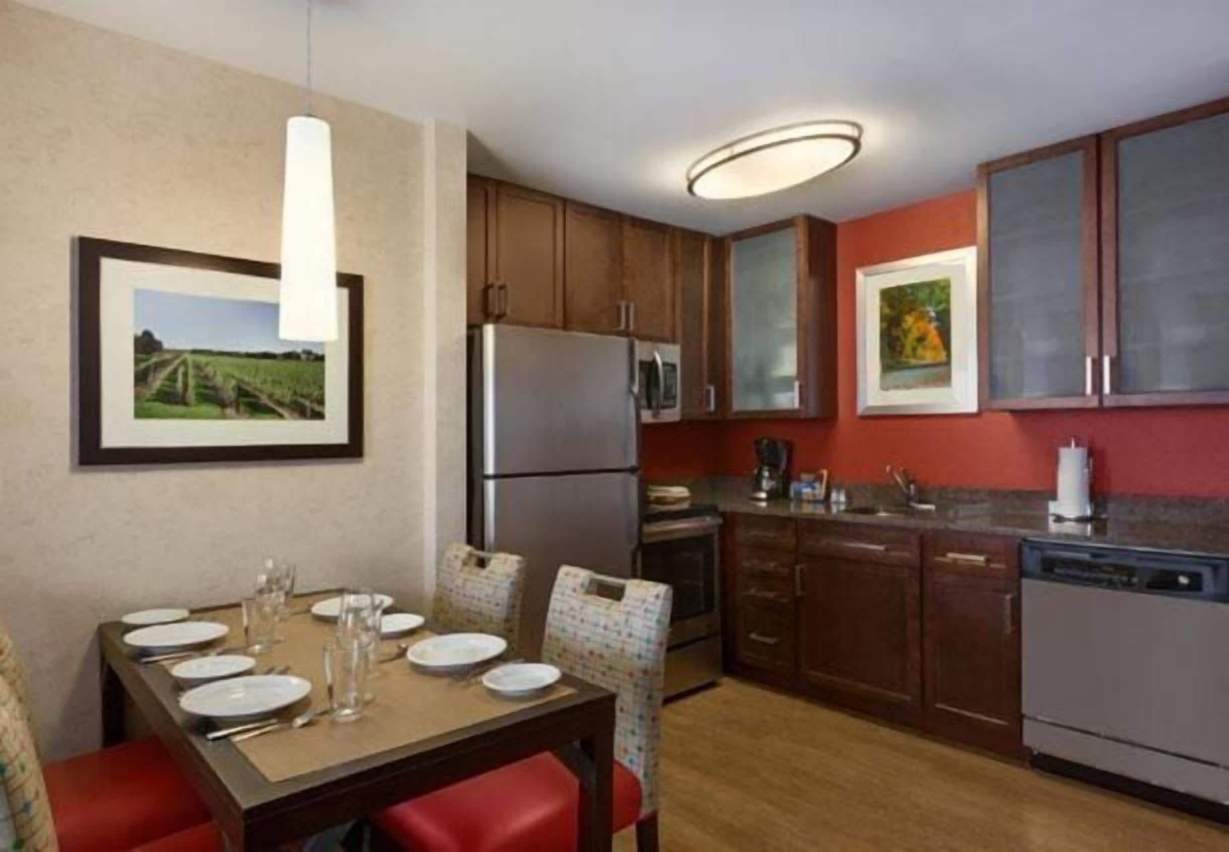 A compact kitchen with wooden cabinets, a refrigerator, microwave, and a dishwasher.