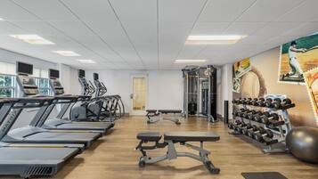 A gym with treadmills, weight machines, and dumbbells.