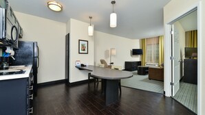 Una habitación de hotel moderna con cocina, una mesa de comedor, un sofá y un televisor.