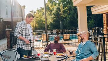 Un área de comedor al aire libre con una piscina al fondo.
