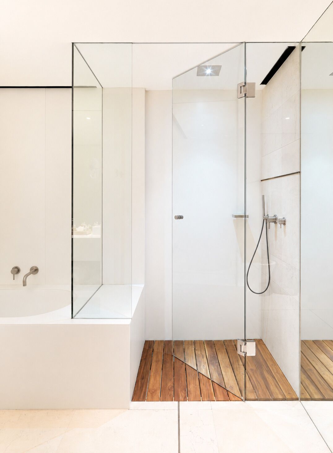 Un baño moderno con ducha de vidrio, piso de madera y bañera blanca.