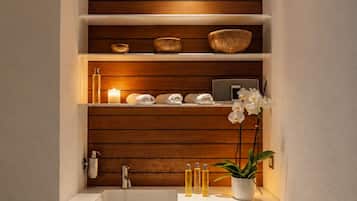Un baño con tocador de madera, lavamanos y estantes sobre el lavabo.
