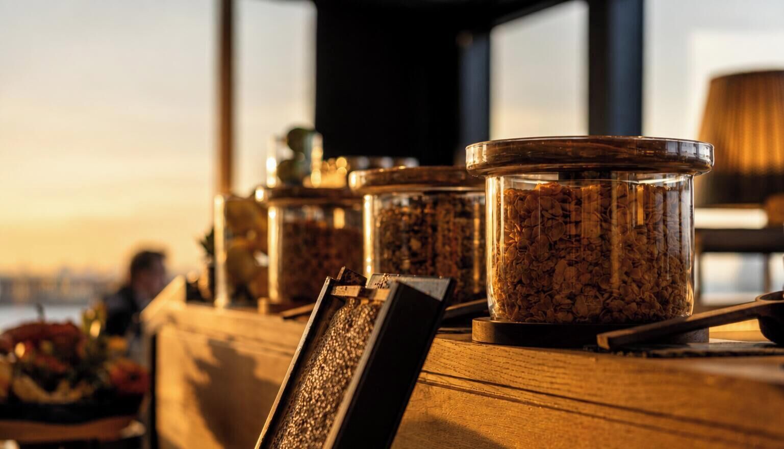 Un comptoir en bois sur lequel sont disposés des bocaux contenant ce qui semble être des céréales ou des graines, peut-être à vendre ou à des fins d’exposition.