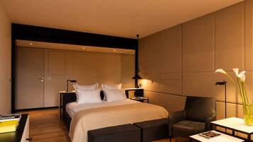 A modern bedroom with a bed, bedside tables, a chair, a small table, and a vase with flowers.