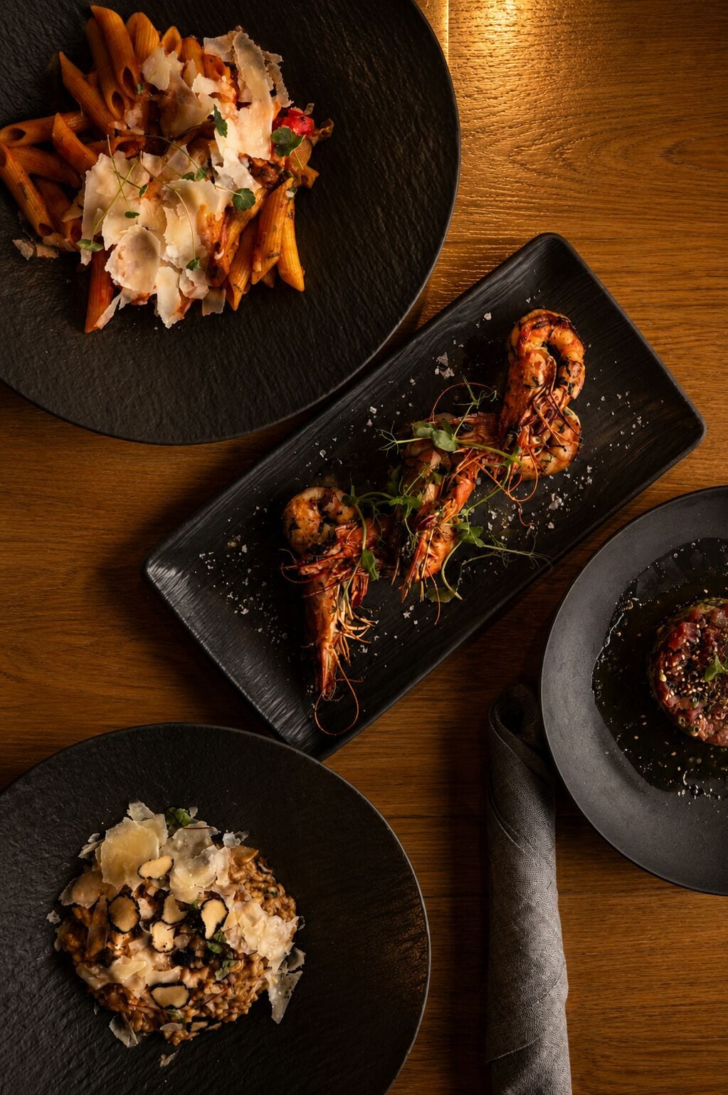 Et bord med tre retter: pasta med ost, grillet rejer og en risotto-lignende ret.