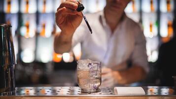 Un bar avec un barman, un verre d’eau avec des glaçons et une bouteille d’alcool.
