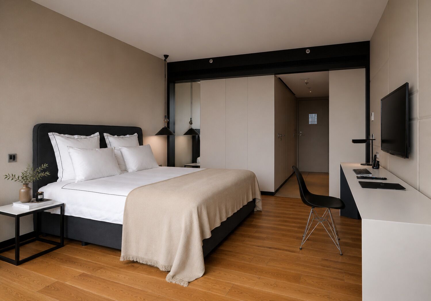 A modern bedroom with a bed, bedside table, lamp, and a desk with a chair.