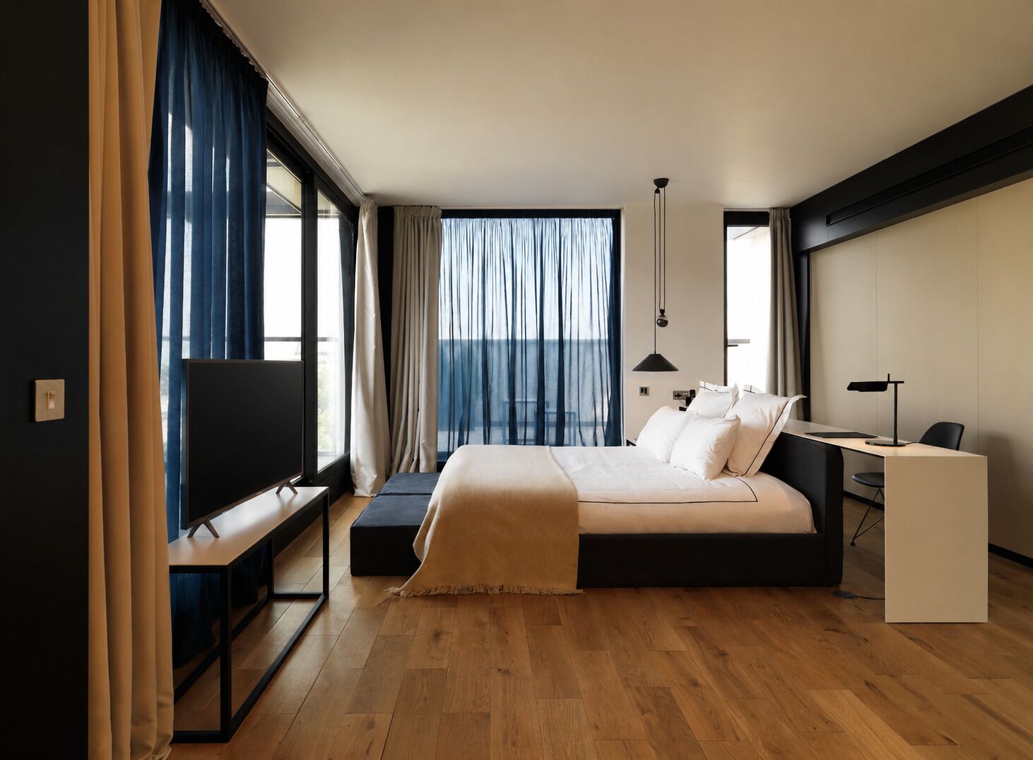 A modern hotel room with a large bed, a desk, and a TV.