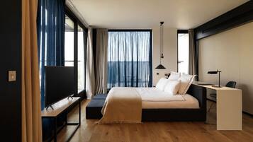A modern hotel room with a large bed, a desk, and a TV.