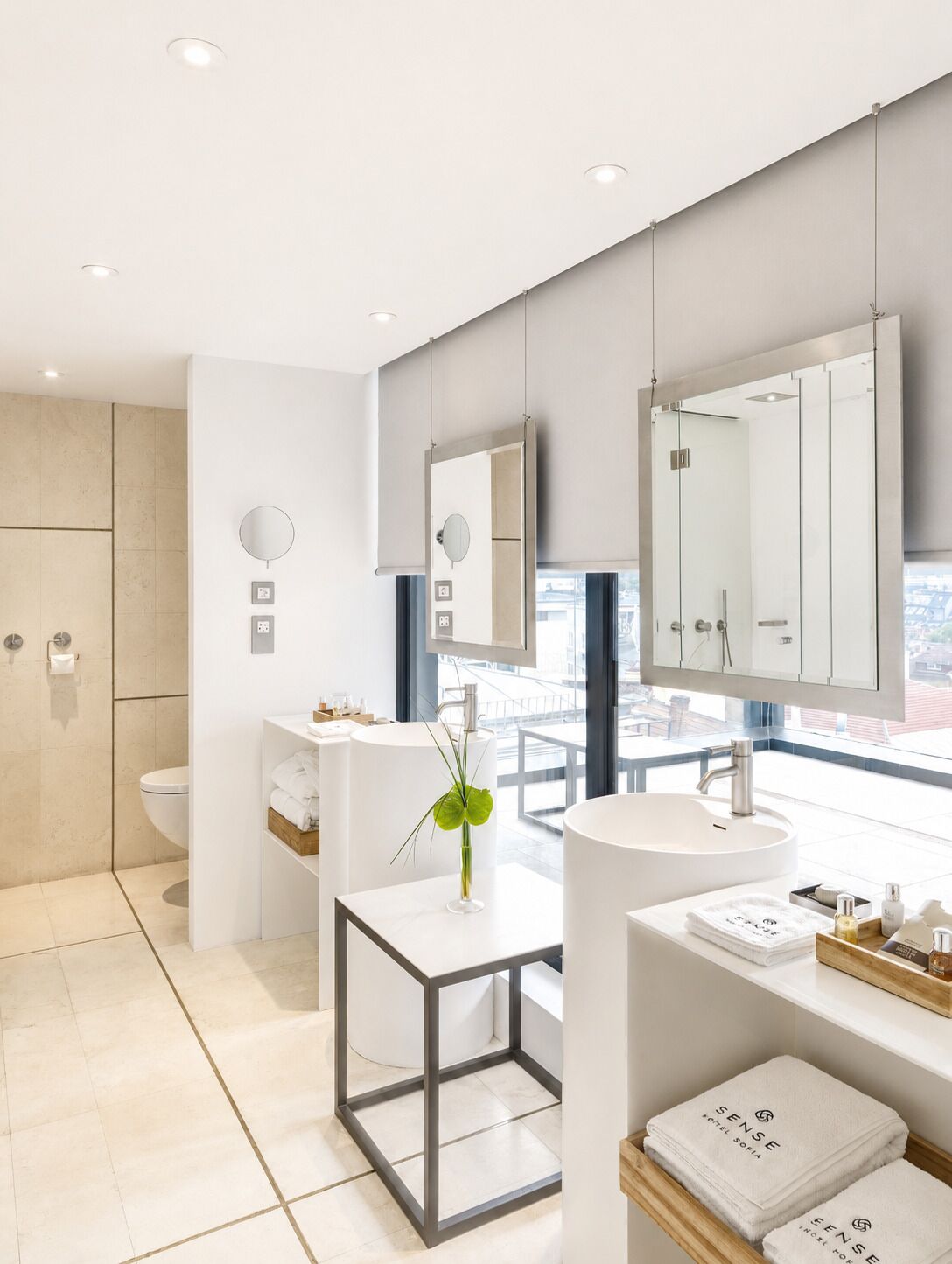 A modern bathroom with a large mirror, a round mirror, a sink, and a toilet.