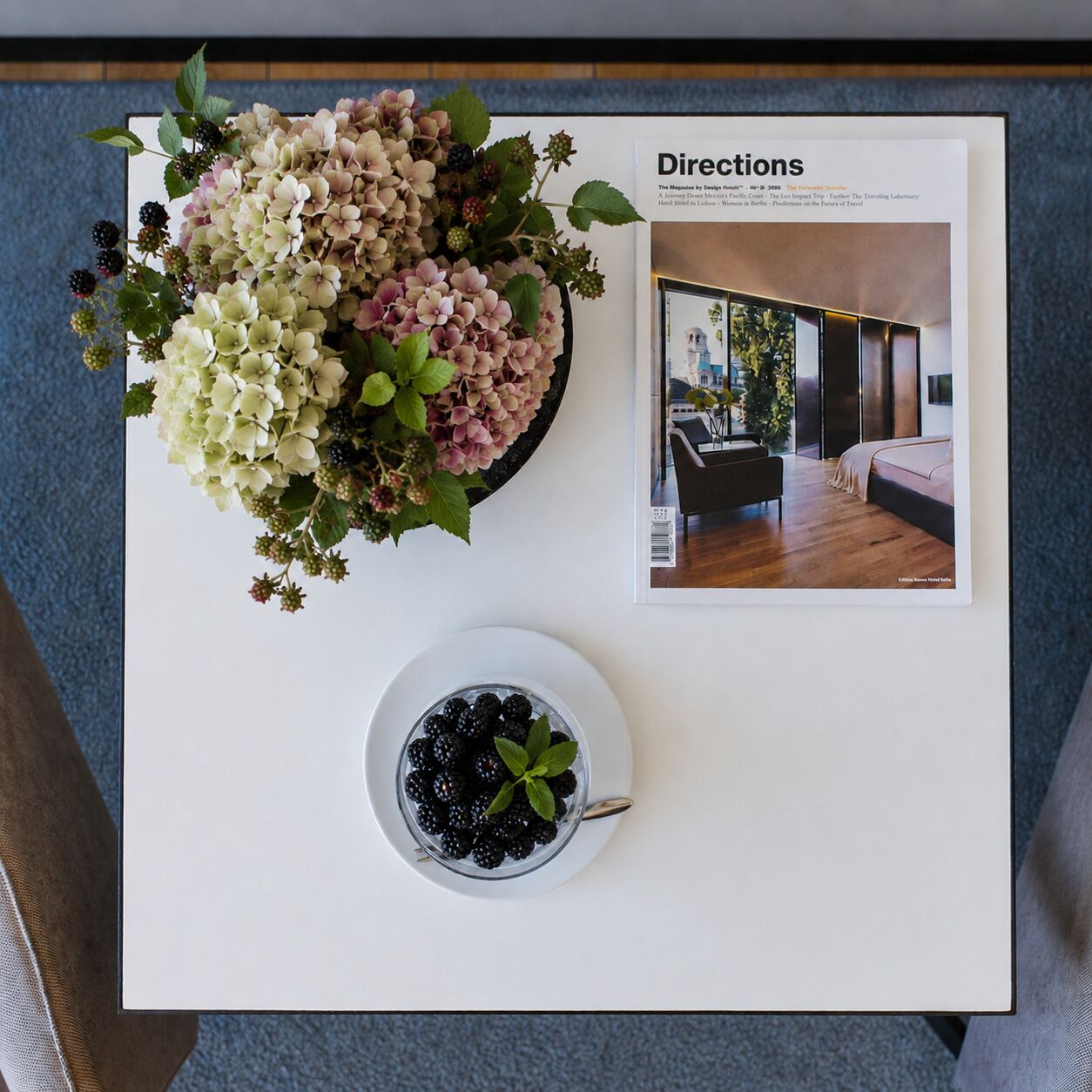 Una revista con una foto de una sala de estar moderna, un cuenco de frambuesas y un arreglo floral.