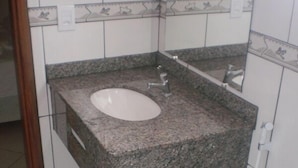 A bathroom with a granite sink, white tiles, and a toilet. - Pousada Cabufa (Cabo Frio)