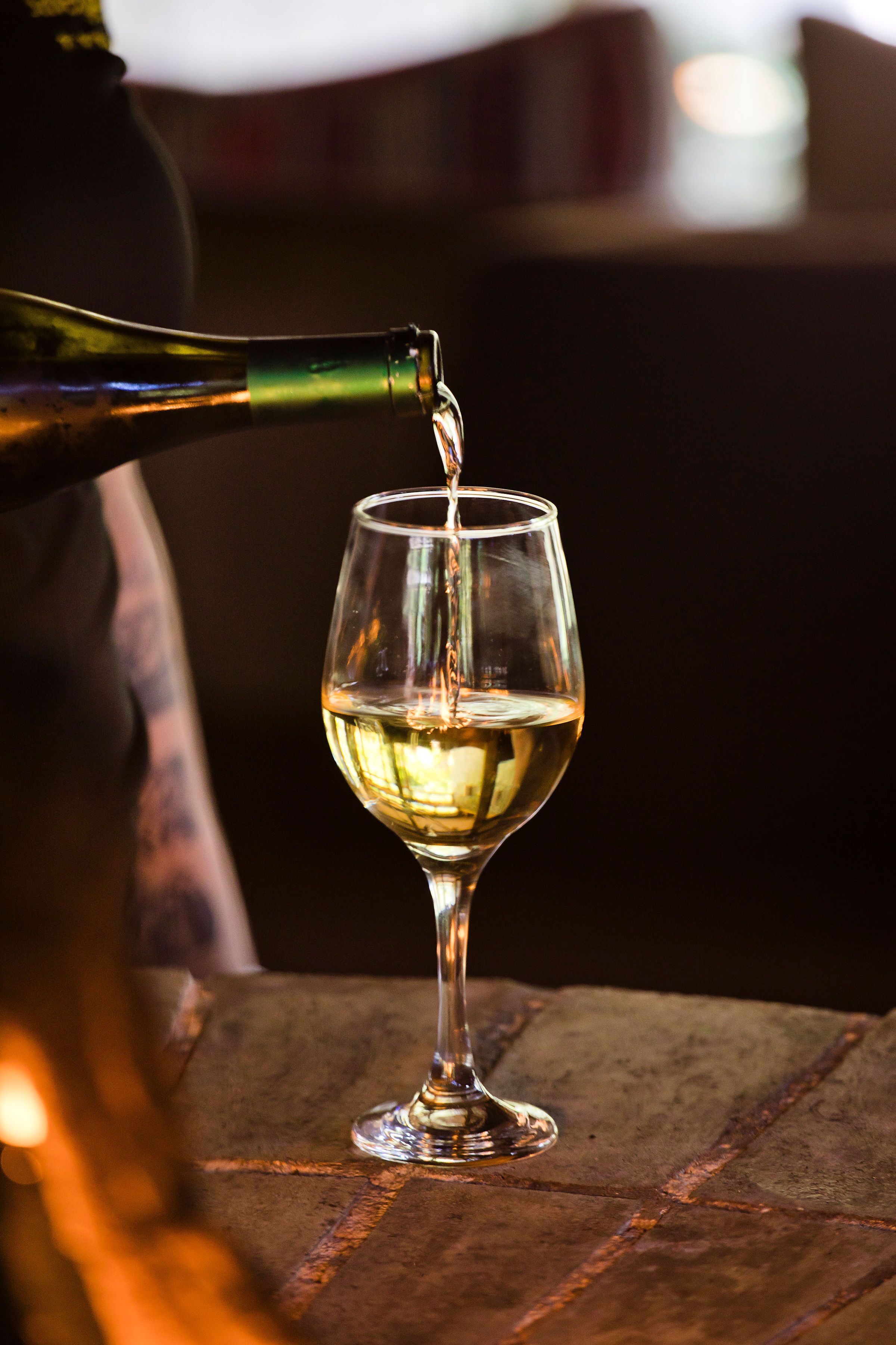 Una copa de vino siendo servida con un líquido transparente sobre una superficie rugosa.