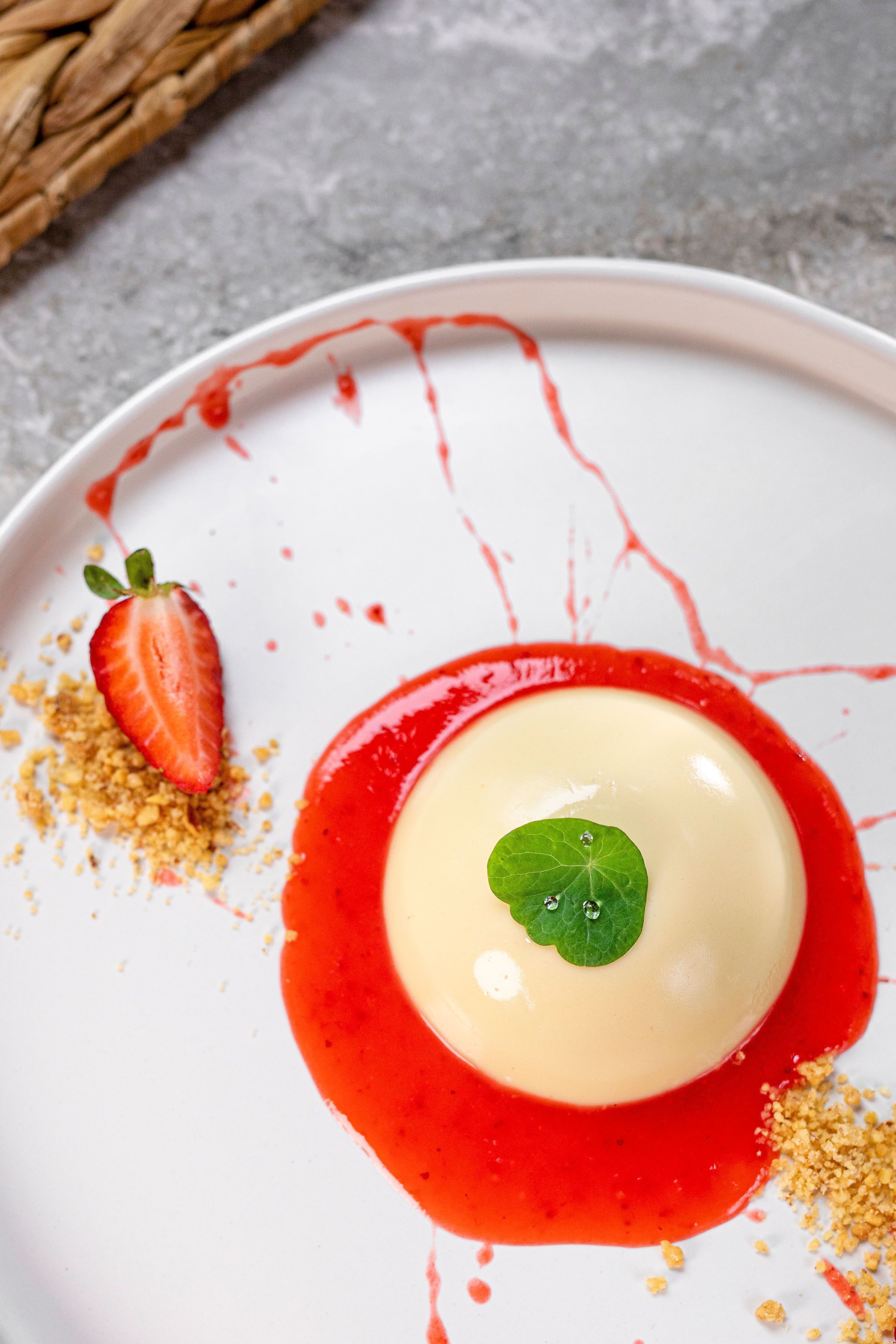 A dessert on a white plate with red sauce and a strawberry garnish.
