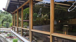 Een modern gebouw met grote glasramen, houten balken en een tuin met vetplanten en rotsen.
