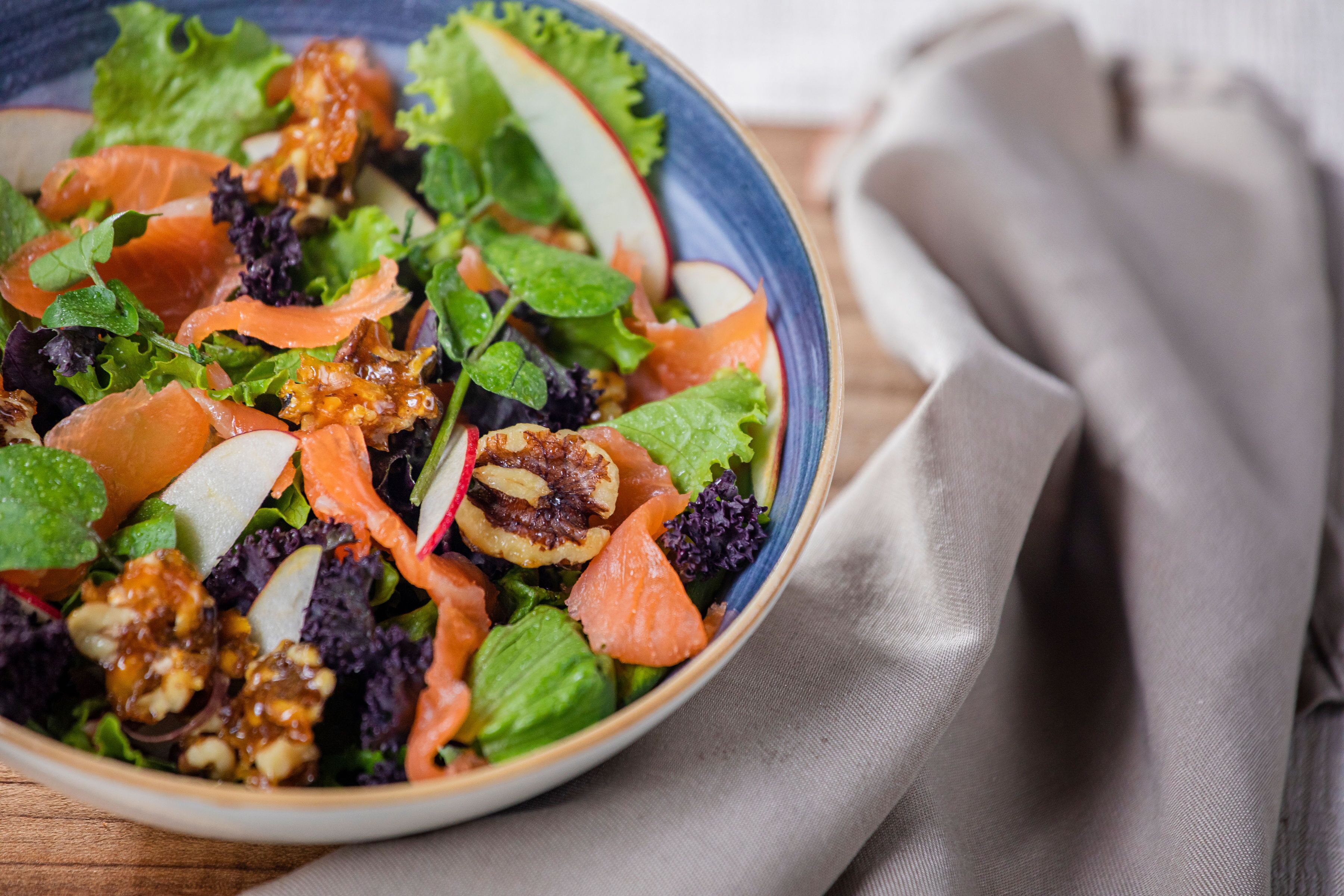 Un tazón de ensalada con diferentes verduras y nueces.