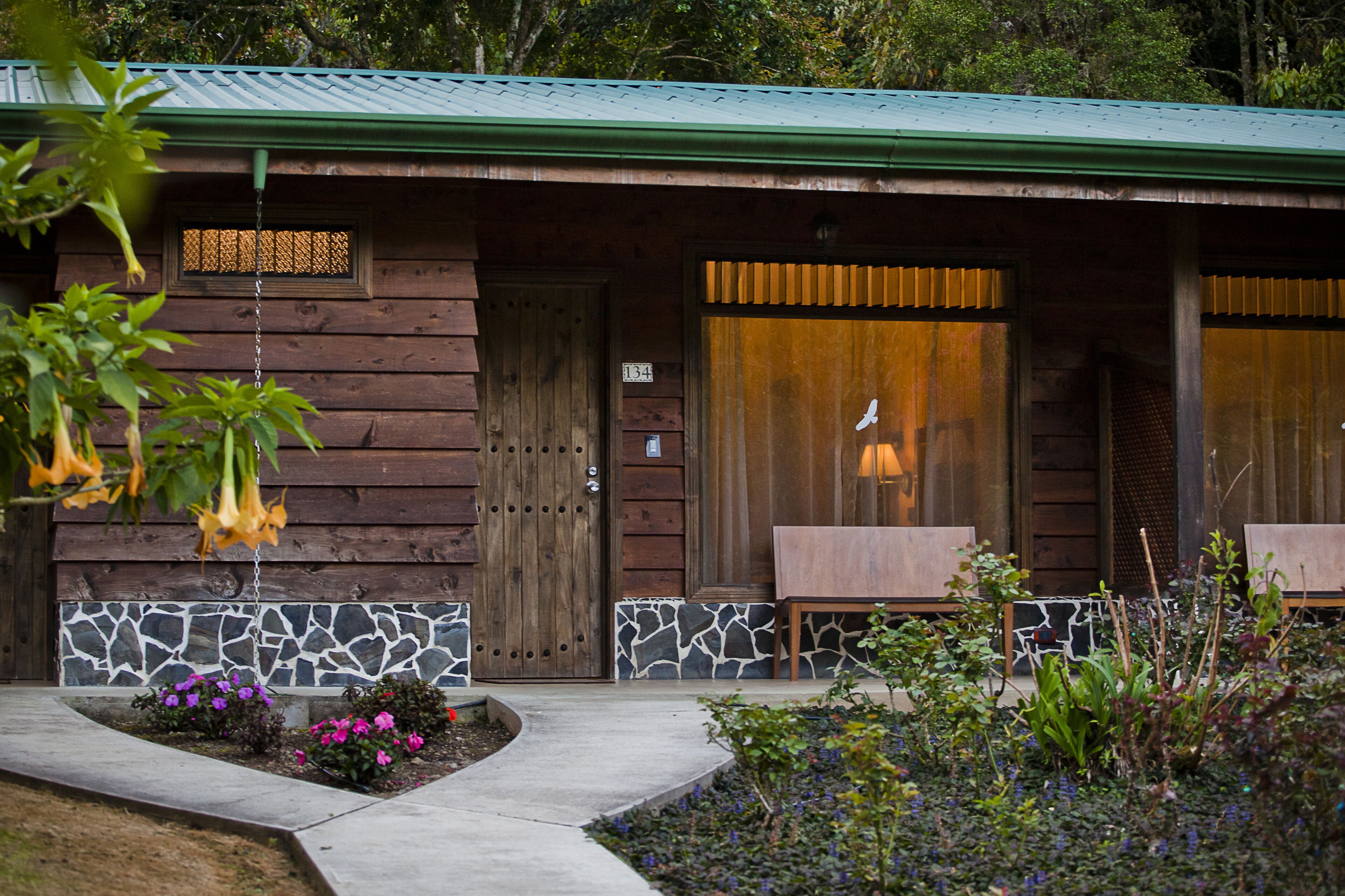 A rustic cabin with a stone foundation, wooden exterior, and a green roof.