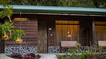 A rustic cabin with a stone foundation, wooden exterior, and a green roof.