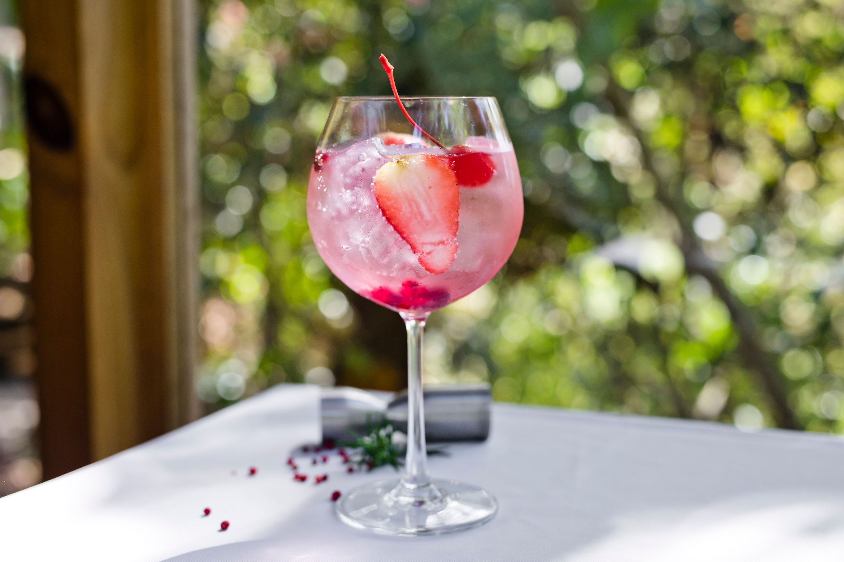 Un verre à cocktail, décoré d’une fraise, posé sur une table blanche.