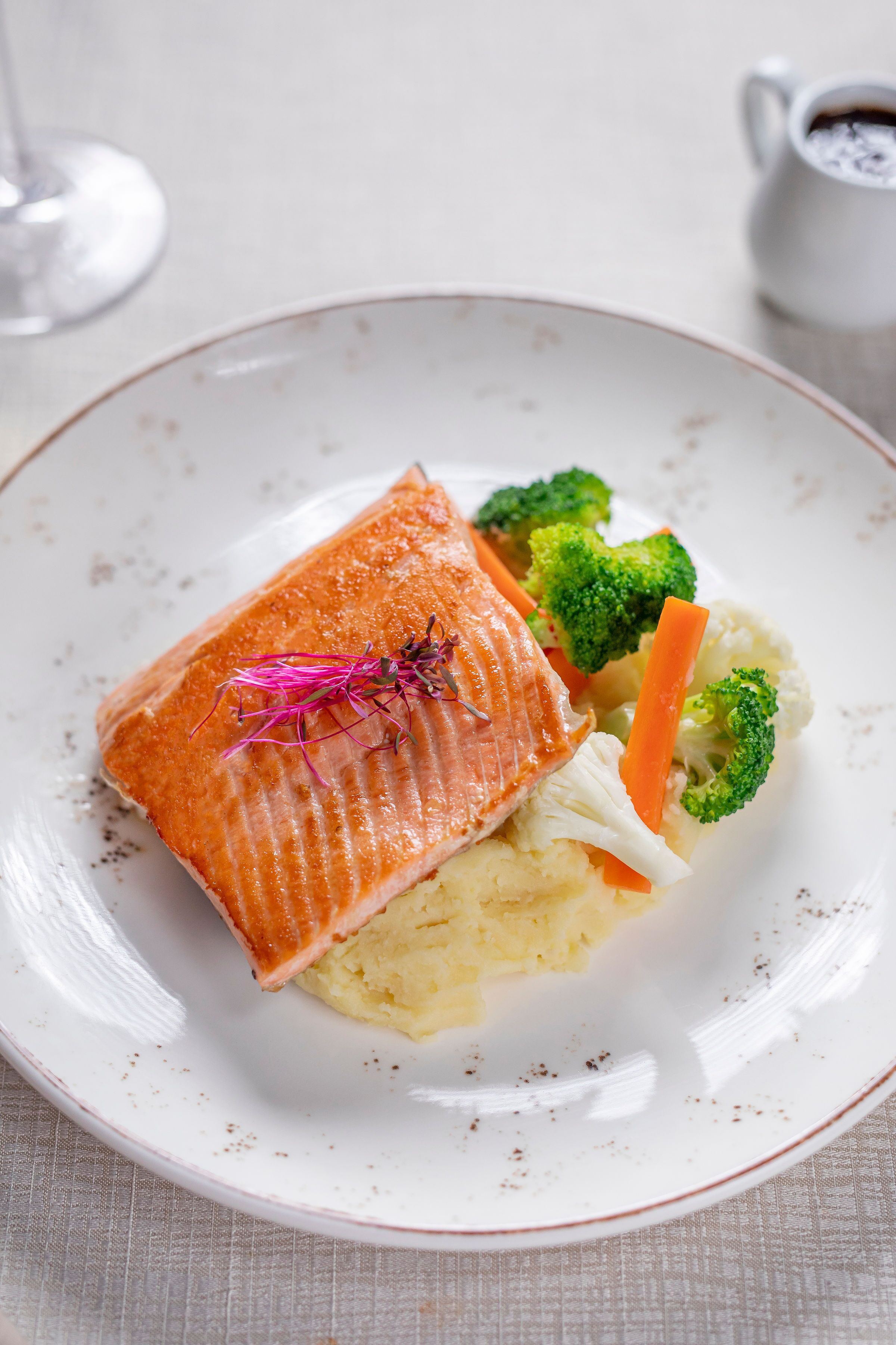 A plate with salmon, broccoli, and carrots.