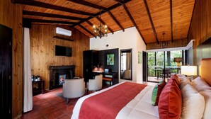Een ruime slaapkamer met een groot bed, een open haard, een bureau en uitzicht op de omgeving.