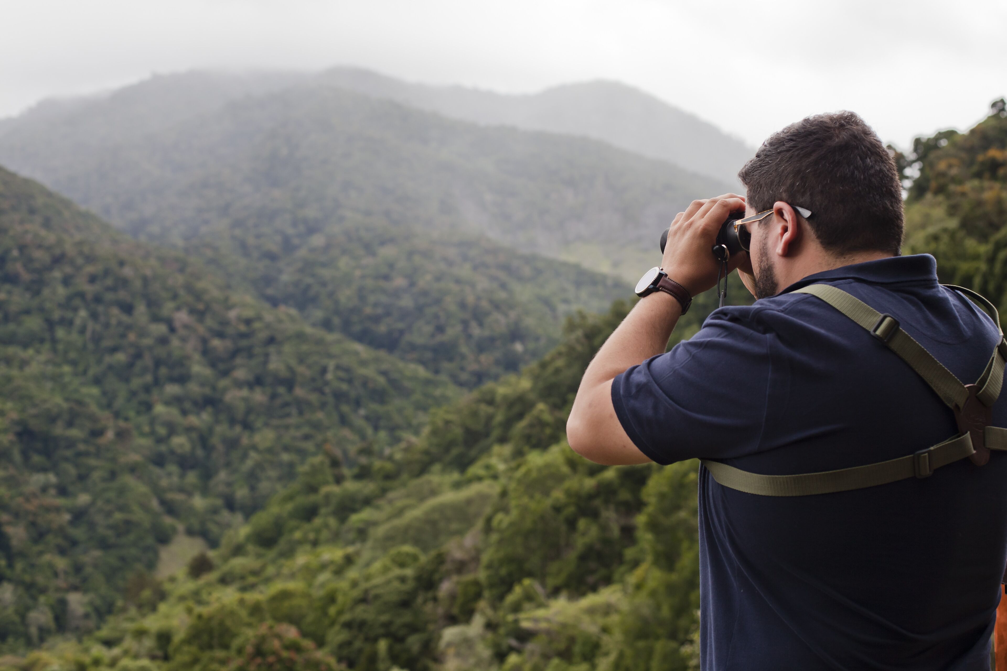 A person taking a photograph of a mountainous landscape.