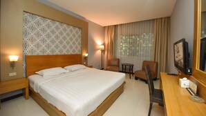 Une chambre d’hôtel avec un grand lit, un bureau avec une chaise, une petite table et un téléviseur.