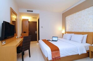 Une chambre d’hôtel comprenant un lit, un bureau avec un ordinateur portable, une télévision et un miroir.