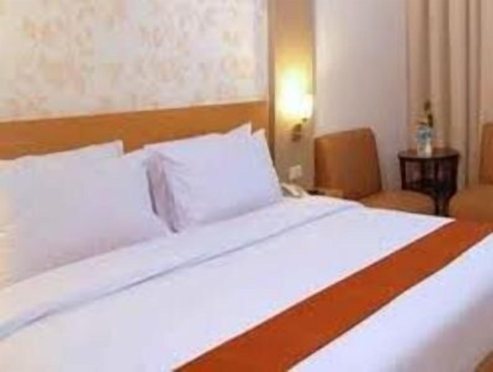 A hotel room with a bed, a nightstand, and a chair.