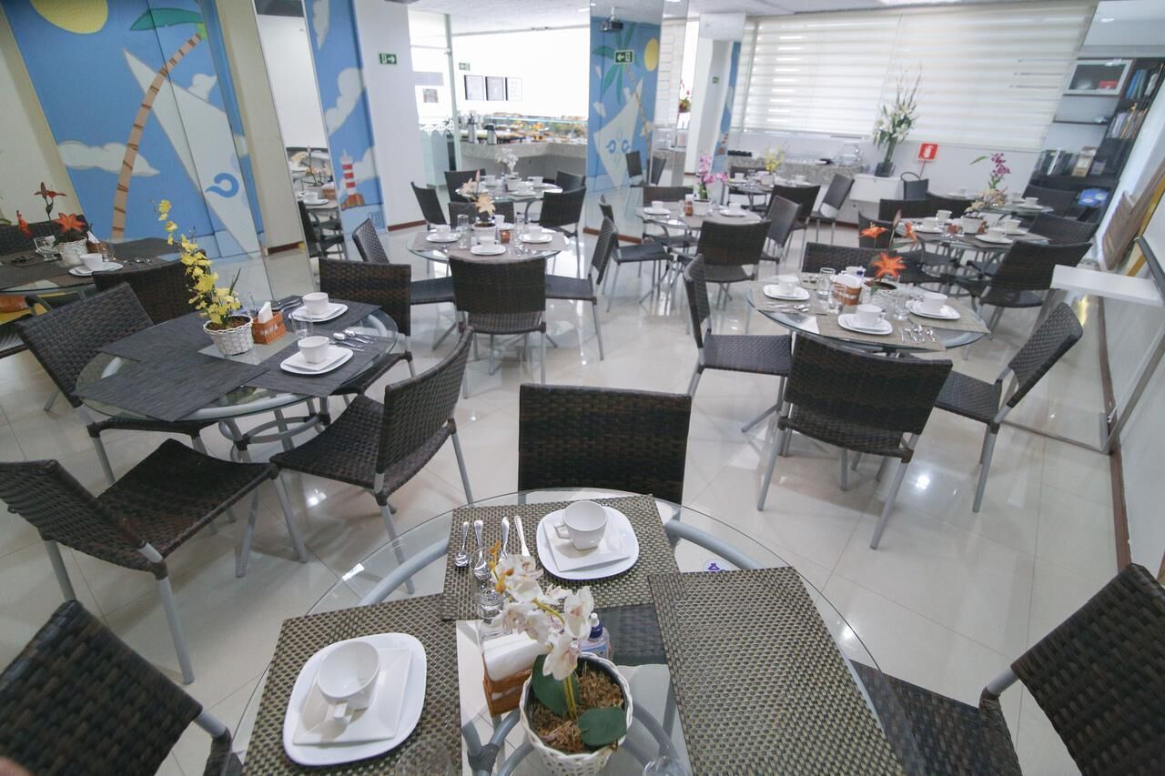 Un restaurant avec des tables rondes et des chaises noires, certaines étant recouvertes de nappes blanches.