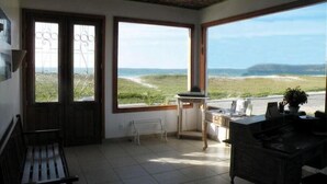 Une chambre avec vue sur la plage, un bureau, une chaise et un banc.