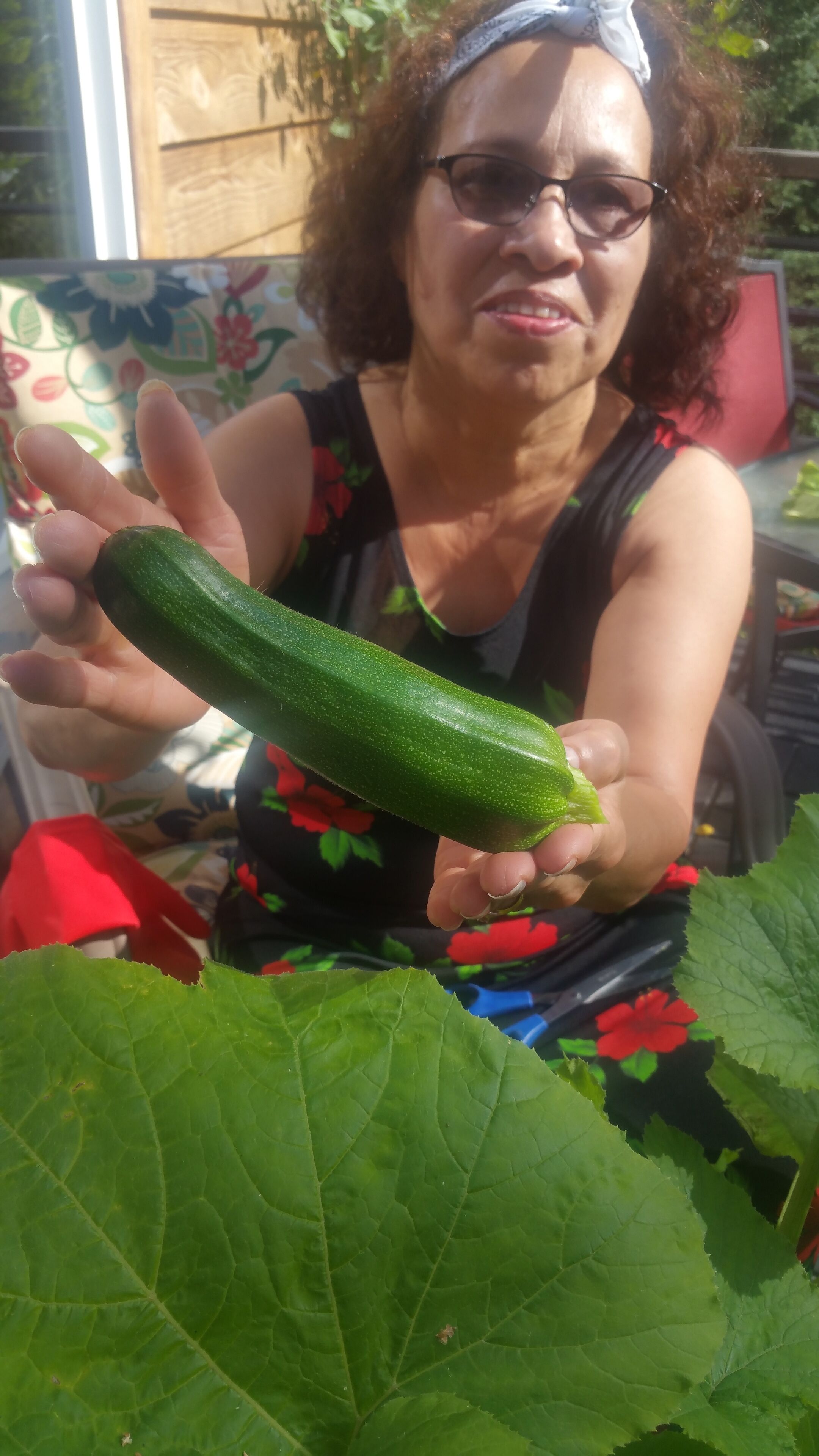 A person holding a large green zucchini.