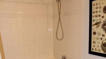 Un baño con bañera, inodoro y un cuadro enmarcado con huevos de pájaro en la pared.