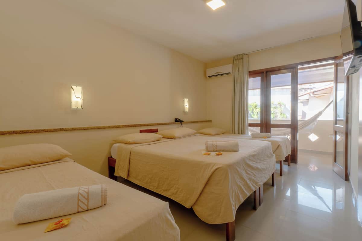 A hotel room with three beds, a large window, and an air conditioning unit.