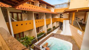 Um hotel com piscina no terraço, várias varandas e uma banheira de hidromassagem.
