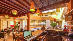 A modern hotel lobby with a bar area, dining space, and a view of the pool. - Rede Andrade Terra Brasil (Porto Seguro)