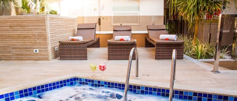 A spa area with a hot tub, lounge chairs, and potted plants.