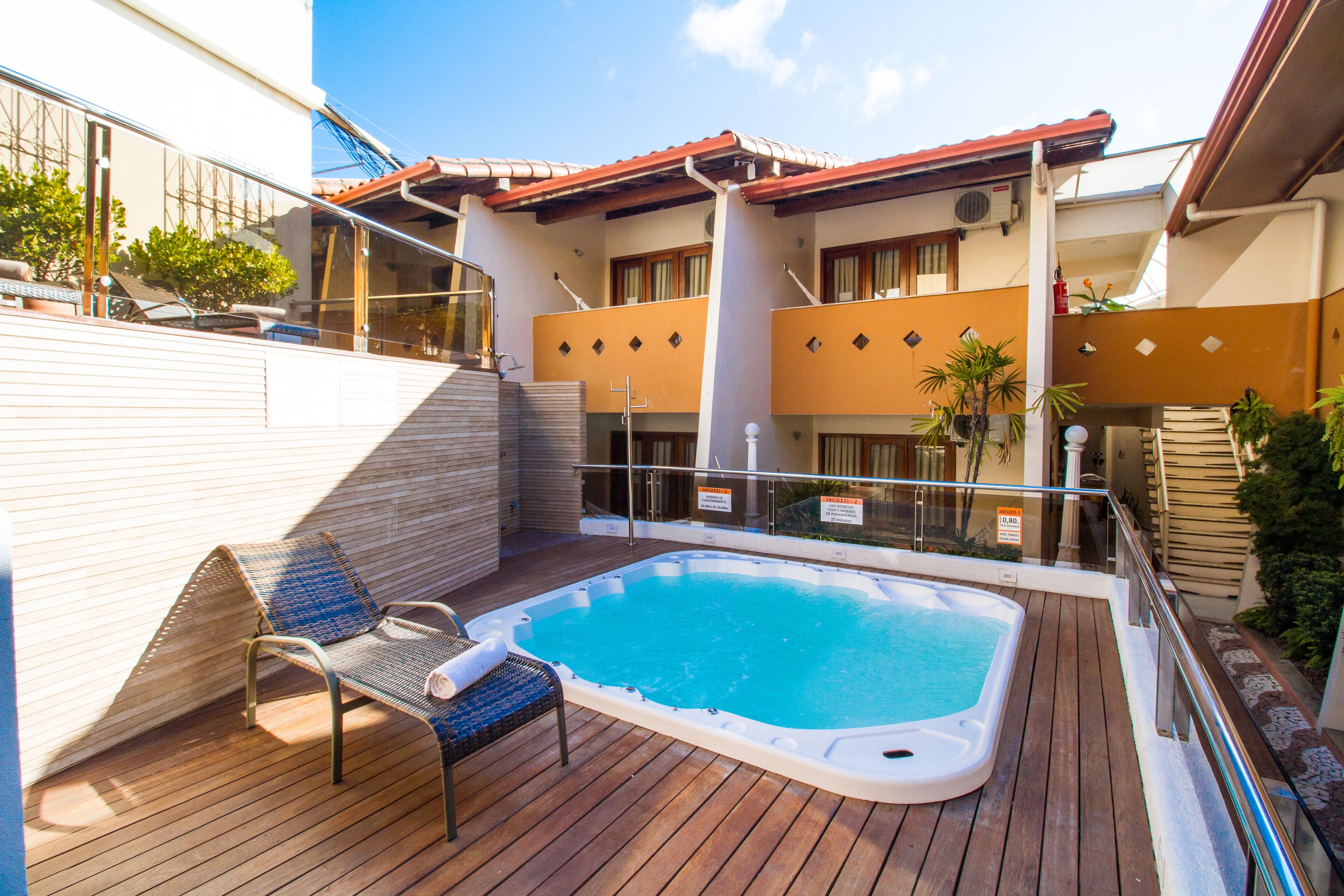 A rooftop pool area with a hot tub, lounge chairs, and a wooden deck.