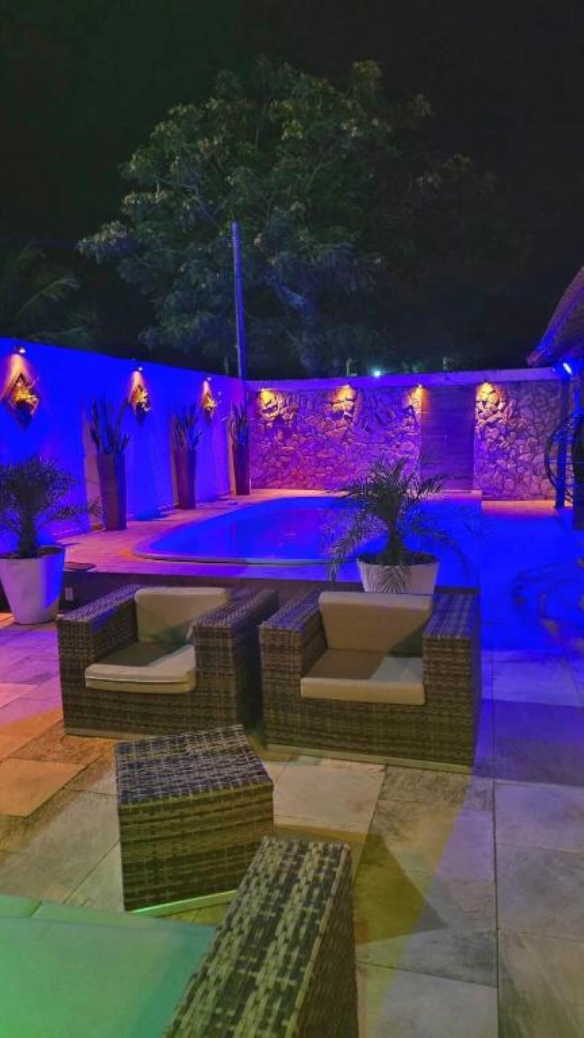 Ein Außenbereich mit Sitzgelegenheiten und Pool, beleuchtet mit blauem und violettem Licht.