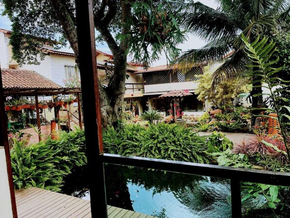 A lush garden with a variety of plants and a small pond. - Pousada Bon Vivant (Cabo Frio)
