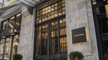 Un edificio histórico con una puerta de entrada negra, un letrero que dice “CORINNE” y plantas en macetas en la acera.