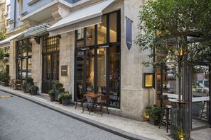 A building with a stone facade, large windows, and outdoor seating with tables and chairs. - Corinne Art & Boutique Hotel (Istanbul)
