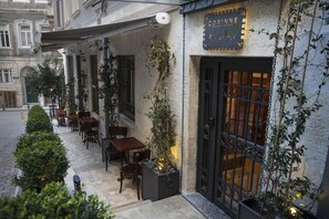 Ein Café mit Terrassensitzgelegenheiten, einem Schild mit der Aufschrift "CORVNE gallery" und einem schmiedeeisernen Tor.