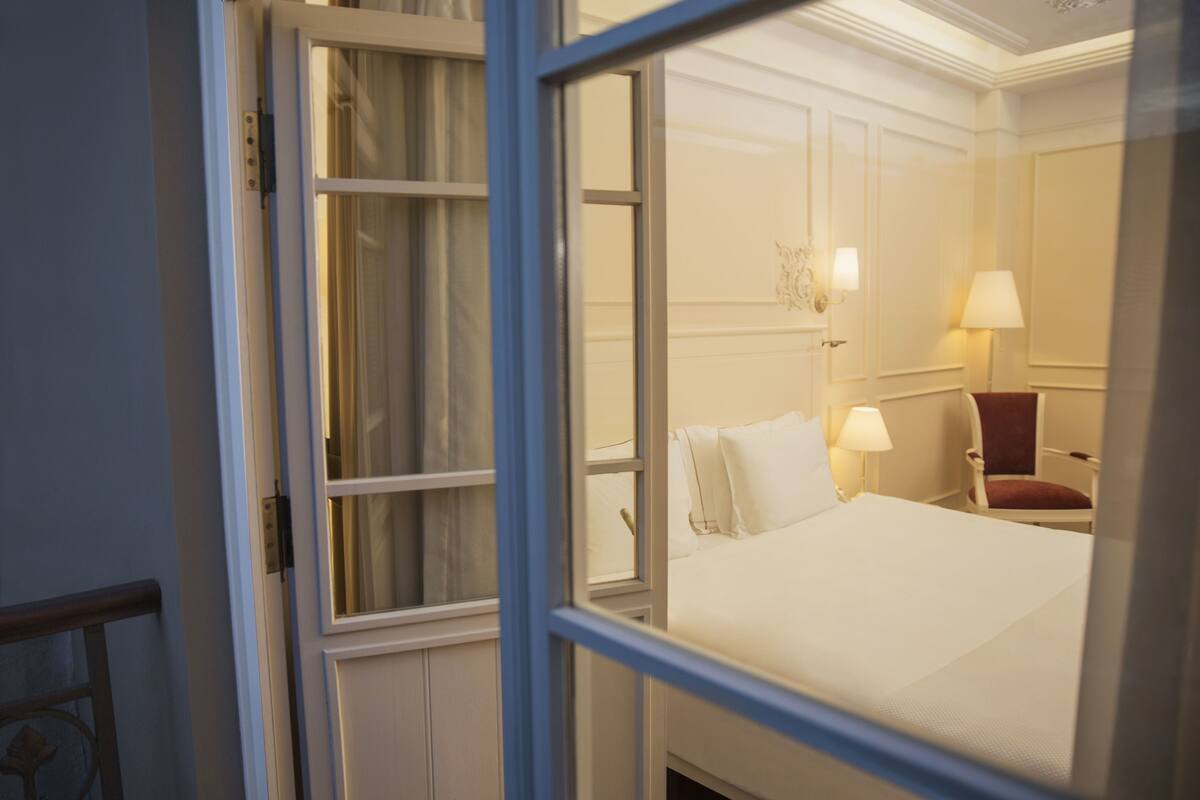A hotel room with a bed, a chair, and a lamp.