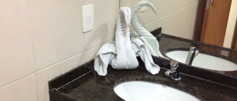 Un baño con dos lavamanos, un perchero para toallas y un espejo.