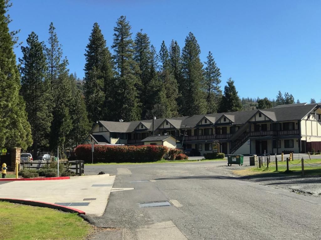 A hotel with multiple buildings, a parking lot, and a forested area in the background.
